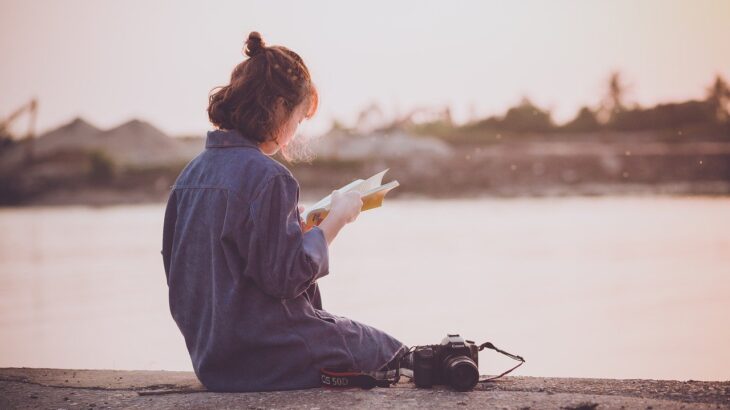 川辺で本を読む女性